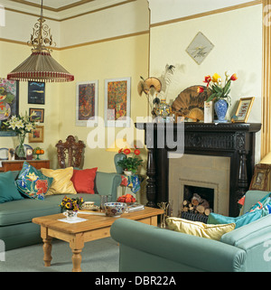 Blauen Sofas und Kiefer Couchtisch im Wohnzimmer blass gelbe Wirtschaft-Stil-Stadthaus mit schwarzen edwardianischen Stil Kamin Stockfoto