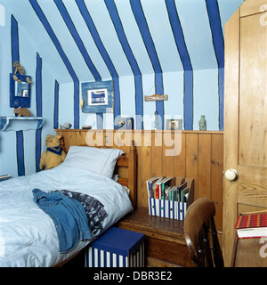 Breiten blaue Streifen gemalt an der Hütte Kinderzimmer mit Einzelbett gegen hölzerne Dado Zunge + Groove-Verkleidung Stockfoto