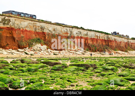 Hunstanton Strand mit roten und weißen Kreide gestreifte Felsen und Algen Algen bedeckten Felsen sichtbar Ebbe, Norfolk, England Stockfoto