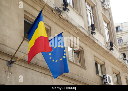 EU und rumänische Flaggen hängen von Polen auf der Außenseite eines Gebäudes Stockfoto