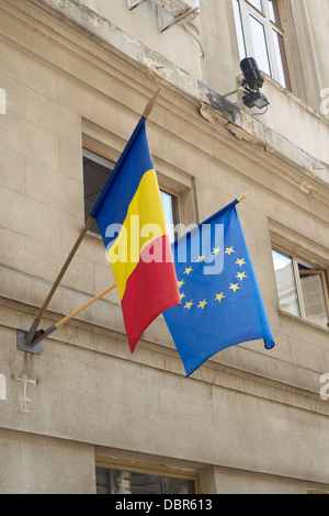 EU und rumänische Flaggen hängen von Polen auf der Außenseite eines Gebäudes Stockfoto