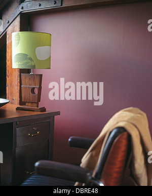 Aus Holz 50er Jahre Stil Lampe mit Grünton auf Schreibtisch in lila Loft Conversion Studie mit Beige Wurf auf Lederstuhl Stockfoto