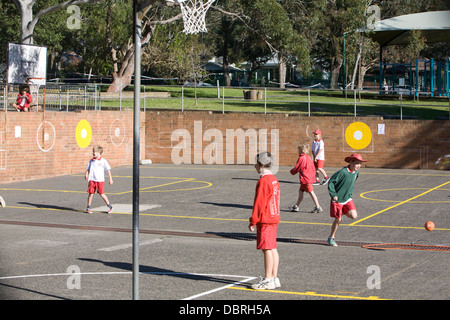Junge Schüler einer australischen Grundschule in Sydney spielen während der Mittagspause Sport auf dem Schulhof in Sydney, Australien Stockfoto