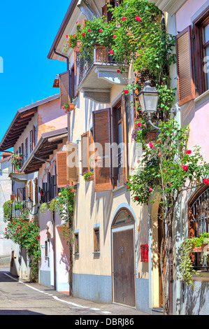 Vertikal ausgerichtete Bild des typischen italienischen Haus mit Balkon und Jalousien, dekoriert mit Blumen in der Stadt von La Morra in Italien. Stockfoto