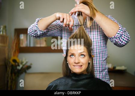weiblichen Kunden im Friseur Shop unsicher schneiden Haare und Lippen beißen Stockfoto
