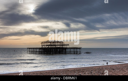 Brighton West Pier Wahrzeichen und Touristenattraktion mit einer Silhouette vor dem Sonnenuntergang mit einer Einzelfigur am Ufer, Brighton, Sussex Stockfoto