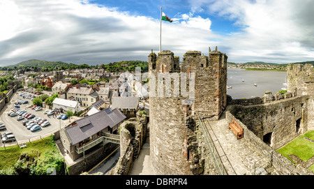 CONWY, Wales – Ein Panoramablick von den Stadtmauern von Conwy Castle, einer mittelalterlichen Festung aus dem 13. Jahrhundert in Nordwales, Großbritannien. Die Szene umfasst einige der imposanten Türme der Burg im Vordergrund, wobei die historische Stadt Conwy und der gewundene Fluss Conwy in der Ferne sichtbar sind. Dieses UNESCO-Weltkulturerbe, erbaut von König Eduard I., bietet einen beeindruckenden Blick auf die umliegende Landschaft und zeigt die strategische Bedeutung seiner Lage. Stockfoto