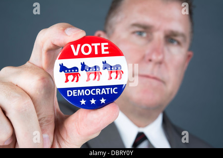 Ein Politiker hält eine demokratische Abstimmung Abzeichen Förderung seiner Pundants zu stimmen. Stockfoto