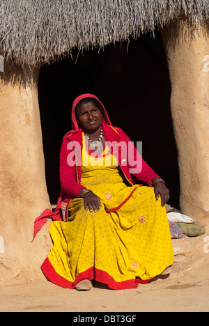 Eine Frau in einen hellen gelben Sari sitzen vor ihrem Lehmhütte am 27. Februar 2013 in Jaisalmer, Indien. Stockfoto