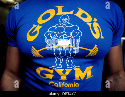 Ein Muskel-Mann trägt ein T-shirt mit dem Logo für Golds Gym, weltweit Fitness-Zentren gegründet 1965 durch Joe Gold in Venice Beach, Kalifornien, USA. Stockfoto