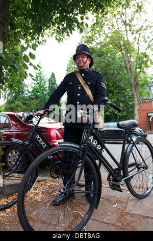 Woodhall Spa. 4. August 2013. Woodhall Spa 1940er Wochenende 08.04.2013 Lincolnshire Dorf UK England. Anwohner, gekleidet in traditionellen 1940 Krieg Mal Outfits Mann verkleidet als Polizist hält Fahrräder Credit Fahrräder: Paul Thompson Live News/Alamy Live News Stockfoto