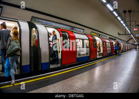 Londoner U-Bahn - Reisende/Pendler boarding Kutschen. Leere Plattform mit der Bahn über den Bahnhof verlassen. England, UK. Stockfoto