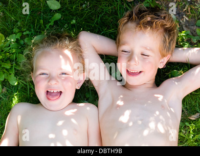 Jungen und Mädchen auf der Wiese liegen und lachen. Das Foto ist im Freien aufgenommen. Stockfoto