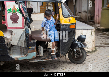 Kleine indische Junge spielt auf Autorikscha verkrüppelt Beinschienen Stockfoto