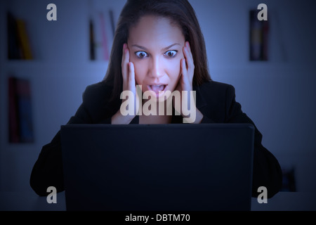 Geschäftsfrau in Panik Blick auf einem Computer-Bildschirm in einem dunklen Raum Stockfoto