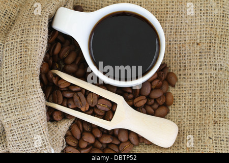 Kaffeebohnen in Jute-Tasche und eine Tasse schwarzen Kaffee Stockfoto