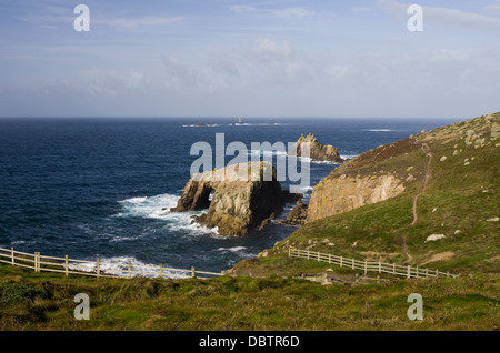 Ein Meer Szene in der Nähe von Endland mit Fußweg entlang der Küste und felsigen Inseln und ein Leuchtturm in der Ferne. Sonniger Tag. Stockfoto