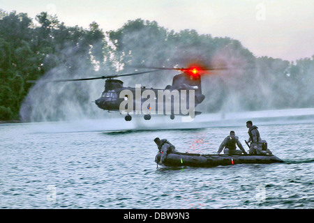 Ein US-Armee CH-47 Chinook fällt Boje Markierungen wie Taucher aus 511th Engineer Dive Ablösung während Betrieb Fluss Angriffs 24. Juli 2013 in Fort Chaffee, Arkansas blicken, auf. Stockfoto