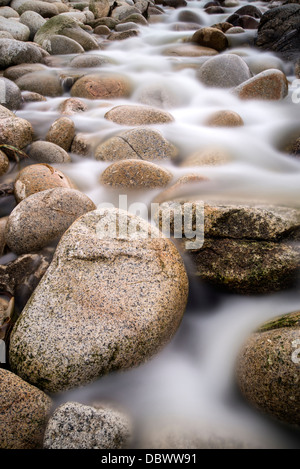 Strom fließt über Wasser getragen Runde Felsen Stockfoto