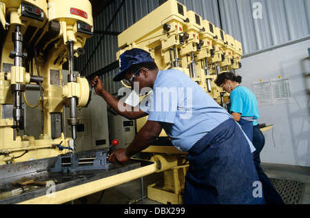 1980ER JAHREN AFROAMERIKANISCHE MANN WORKER BETRIEB INDUSTRIE BOHRMASCHINE MASCHINEN FRAU OPERATOR IM HINTERGRUND Stockfoto