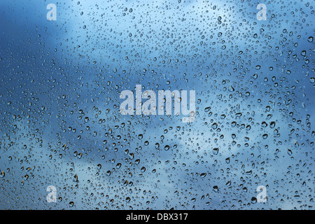 Wassertropfen auf Fenster mit dunklen Wolken im Hintergrund Stockfoto