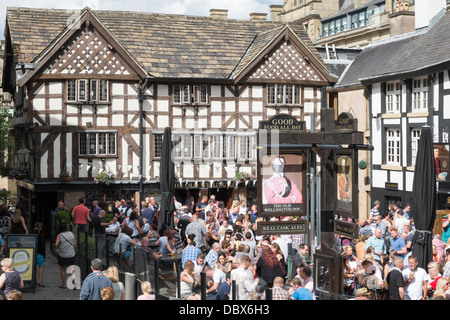 Massen von Menschen trinken außerhalb der alten Fachwerkhäusern aus dem 16. Jahrhundert Wellington Inn 1552, im Sommer, im alten Shambles Square Manchester England Großbritannien Großbritannien Stockfoto