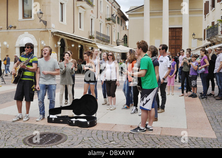 Eine Gruppe von jungen Straßenmusiker unterhalten die Massen auf der Piazza Giacomo Matteotti in Bardolino am Gardasee. Stockfoto