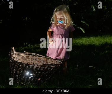 Kind blondes Mädchen fand einen Schatz im Weidenkorb Stockfoto