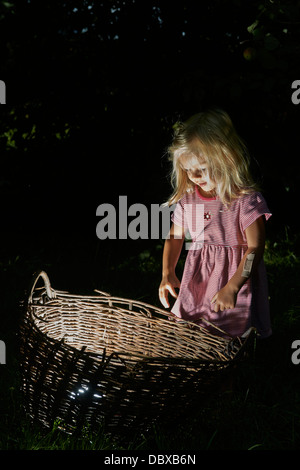 Kind blondes Mädchen fand einen Schatz im Weidenkorb Stockfoto