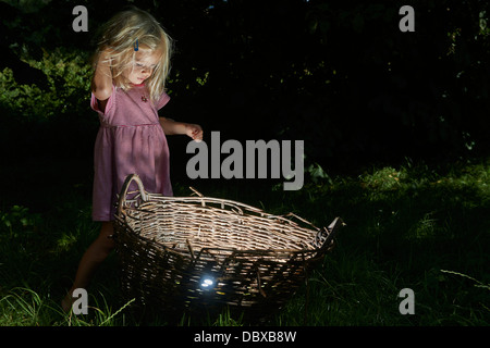 Kind blondes Mädchen fand einen Schatz im Weidenkorb Stockfoto