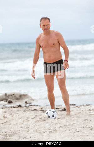 glückliche Familie Vater zwei Kinder Fußball spielen auf Strand Sommer Spaß Fußball Stockfoto