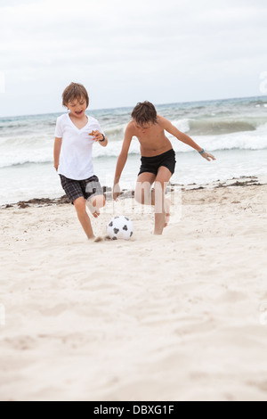 glückliche Familie Vater zwei Kinder Fußball spielen auf Strand Sommer Spaß Fußball Stockfoto