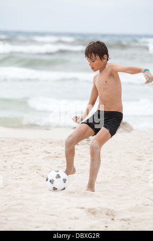 glückliche Familie Vater zwei Kinder Fußball spielen auf Strand Sommer Spaß Fußball Stockfoto