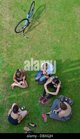 Gruppe von jungen Studenten sitzen am Ufer an Göring Schleuse Goring-on-Thames, Oxfordshire, England, Vereinigtes Königreich Stockfoto