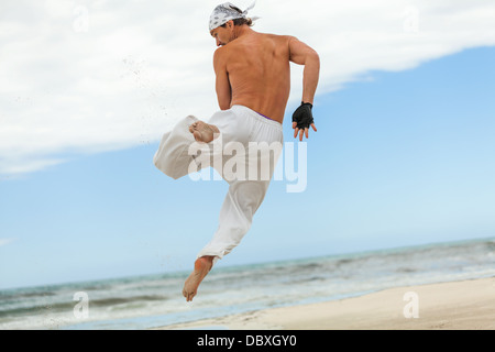 Mann springt Sport Karate Martial Arts Kampf Kick Sprung Strand im Sommer Stockfoto