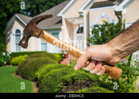 Mannes Hand mit Hammer vor der ein Haus darauf hinweist, Heimwerker- und Wartung. Stockfoto