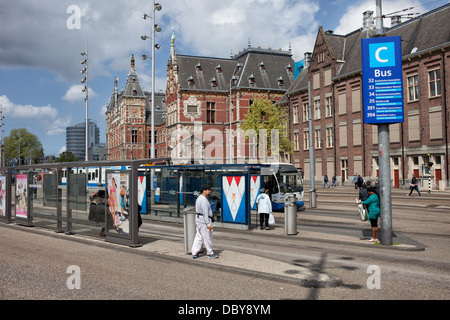 Städtische Infrastruktur, Bushaltestellen und Central Train Station Neo-Renaissance Gebäude in Amsterdam, Holland, Niederlande. Stockfoto