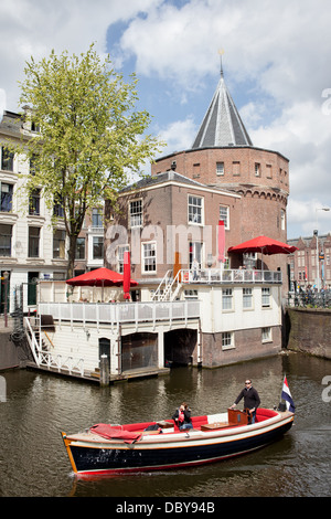 Weinende Turm (Schreierstoren) und Boot auf Geldersekade Kanal in Amsterdam, Niederlande Stockfoto