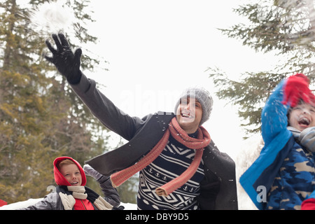 Verspielte Vater und Söhne werfen Schnee Stockfoto