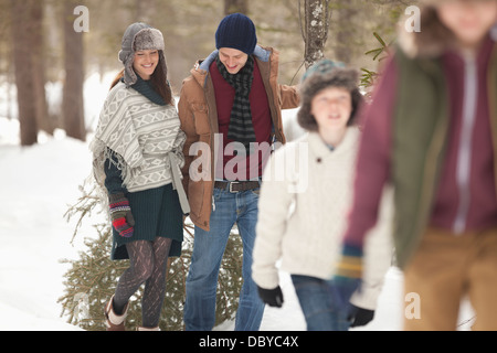Glückliche Familie ziehen frischen Weihnachtsbaum im verschneiten Wald Stockfoto