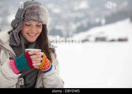 Lächelnde Frau Kaffee trinken im Schnee Stockfoto