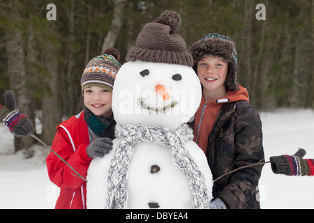 Porträt von glücklichen jungen posiert mit Schneemann Stockfoto