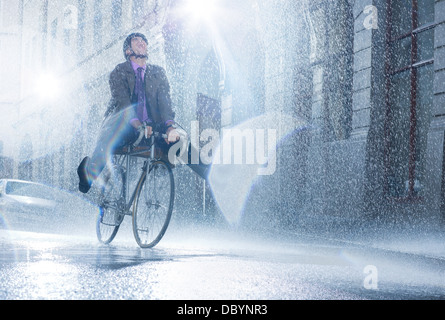 Geschäftsmann Reiten Fahrrad im verregneten Straße Stockfoto