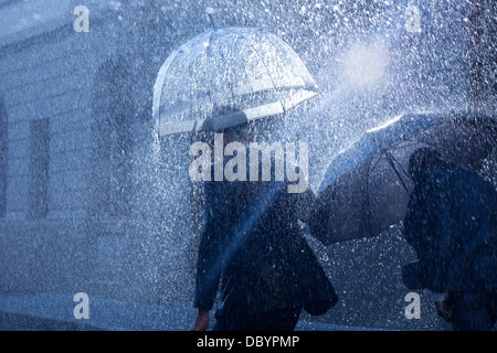 Geschäftsleute mit Sonnenschirmen im Regen Stockfoto