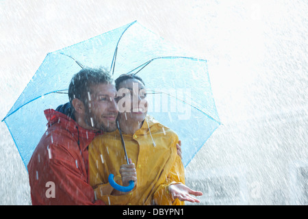 Glückliches Paar unter Dach im Regen Stockfoto