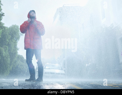 Mann mit Regenmantel im verregneten Straße Stockfoto