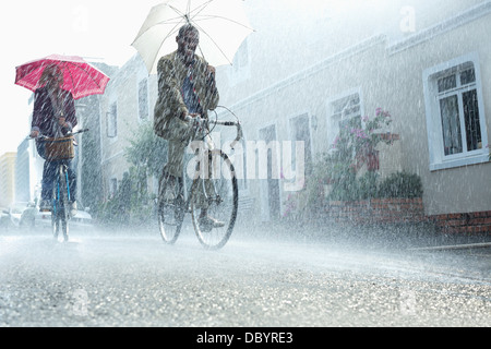 Paar mit Sonnenschirmen Fahrrad im Regen Stockfoto