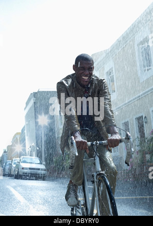 Glücklich Kaufmann Reiten Fahrrad im Regen Stockfoto