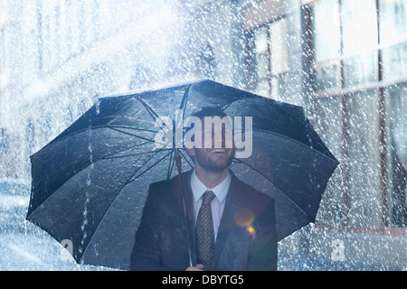 Glücklich Kaufmann unter Dach im Regen Stockfoto