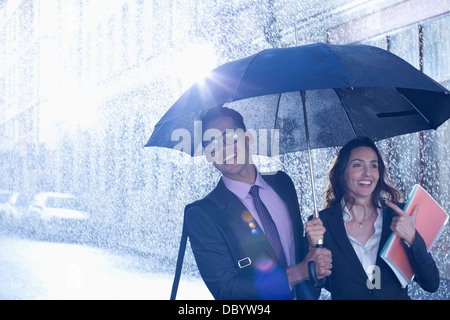 Glücklich Kaufmann und Geschäftsfrau unter Dach im Regen spazieren Stockfoto